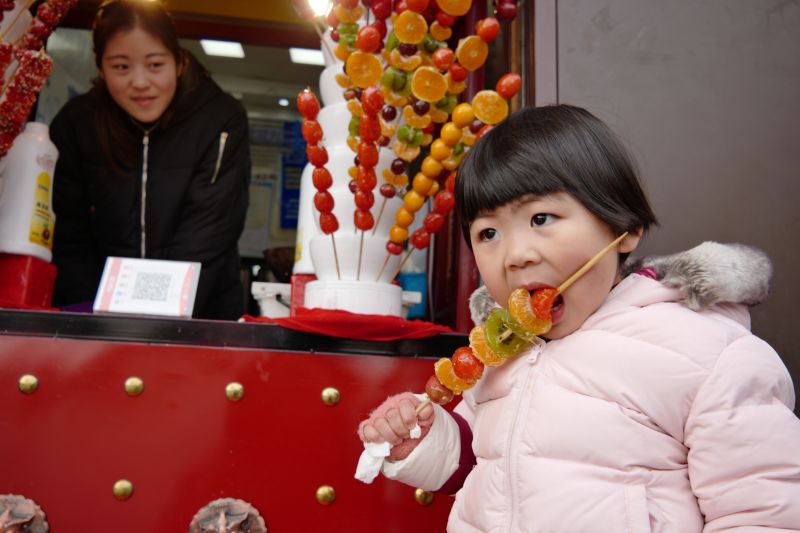 3,1月20日,一名手持冰糖葫芦的女童在夫子庙景区玩耍,传递着浓浓的年